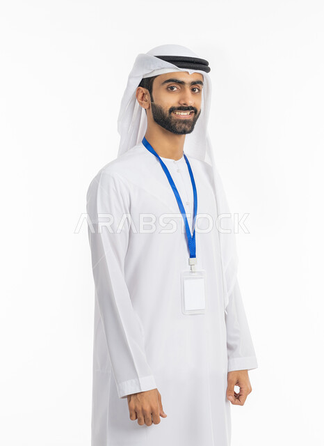 كرت أبيض مستطيل فارغ, ارتداء بادج شخصي, مفهوم الأناقة والرجولة والاهتمام بالمظهر الخارجي, بورتريه لرجل عربي خليجي إماراتي مبتسم يرتدي الكندورة والغترة ينظر إلى الكاميرا ويضع بطاقة شخصية تعريفية بشريط أزرق, خلفية بيضاء