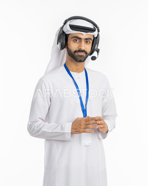 العمل في قسم الدعم الفني, برامج التحدث عن بعد, استخدام تقنية الهيدفون, الرد على اسئلة واستفسارات العملاء, بورتريه لرجل عربي خليجي إماراتي يرتدي الكندورة والغترة الاماراتية يقف بثقة بالنفس, ارتداء بادج شخصي, بطاقة تعريفية شخصية للموظفين, خلفية بيضاء