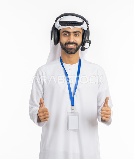 النظر إلى الكاميرا بإيماءات السرور, الرد على اسئلة واستفسارات العملاء في قسم الدعم الفني, بورتريه لرجل عربي خليجي إماراتي مبتسم يرتدي الكندورة والغترة يرفع أصابعه بعلامة الجودة والامتياز, دمج العمل مع التقنية والتكنولوجيا في الحياة العملية, خلفية بيضاء