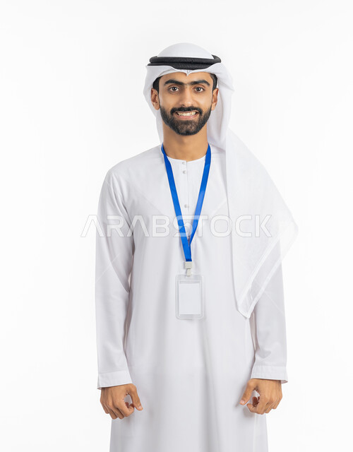 الاهتمام بالمظهر الخارجي والأناقة الرجولية الاماراتية, موك اب بطاقة تعريفية مفرغة باللون الابيض, النظر إلى الكاميرا بتعابير البهجة والفرح، بورتريه لرجل عربي خليجي إماراتي يرتدي الكندورة والغترة الاماراتية يقف بابتسامة, ارتداء بادج شخصي, خلفية بيضاء