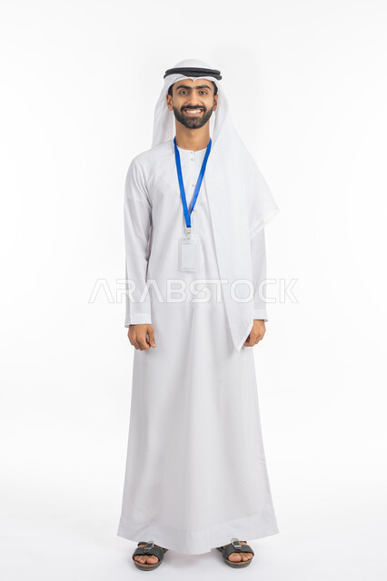 النظر إلى الكاميرا بتعابير البهجة والفرح, موك اب بطاقة تعريفية مفرغة باللون الابيض، بورتريه لرجل عربي خليجي إماراتي يرتدي الكندورة والغترة الاماراتية يقف بابتسامة, ارتداء بادج شخصي, صورة الجسم بالطول الكامل, خلفية بيضاء