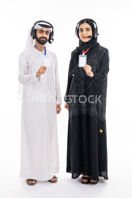 بطاقة تعريفية للموظفين, إبراز الهوية الشخصية, بورتريه لموظف وموظفة عربيين خليجيين إماراتيين يقومان بعرض بطاقة بيضاء مستطيلة فارغة, استخدام تقنية الهيدفون بالرد على اسئلة واستفسارات العميل, العمل في مجال خدمة العملاء, صورة الجسم بالكامل, خلفية بيضاء