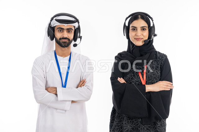 الوقوف بإيماءات أيدي متقاطعة, بورتريه مقرب لإمرأة عربية خليجية اماراتية مبتسمة محجبة ترتدي العباءة تعمل في مجال خدمة العملاء, رجل إماراتي ينظر إلى الكاميرا بثقة, استخدام تقنية الهيدفون والرد على استفسارات واستعلامات الزبائن, مهن ووظائف خليجية، خلفية بيضاء