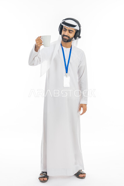 العمل في مجال خدمة العملاء والدعم الفني, استخدام تقنية الهيدفون, الاستمتاع بالمشروبات الساخنة, بورتريه لموظف عربي خليجي إماراتي يرتدي الكندورة والغترة يضع سماعة الاتصال ويمسك بيده كوب من القهوة,  الرد على استفسارات الزبائن، صورة الجسم بالطول الكامل, خلفية بيضاء