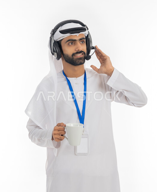 استخدام تقنية الهيدفون، الرد والاستفسارات على الزبائن، بورتريه لرجل عربي خليجي اماراتي يرتدي الكندورة وسماعه الرأس الصوتية يمسك كوب من القهوة، مهن ووظائف إداريه اماراتية, العمل في مكاتب خدمة العملاء, خلفية بيضاء