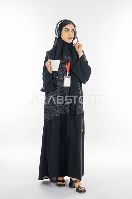 العمل على جذب واستقطاب المزيد من العملاء، الإجابة عن الاستعلامات والاستفسارات, بورتريه لسيدة عربية خليجية اماراتية محجبة ترتدي العباءة السوداء تعمل في مجال خدمة العملاء, إمرأة سعودية تمسك كوب من القهوة وتقوم بالاصغاء لأسئلة الزبون, صورة الجسم بالكامل, خلفية بيضاء