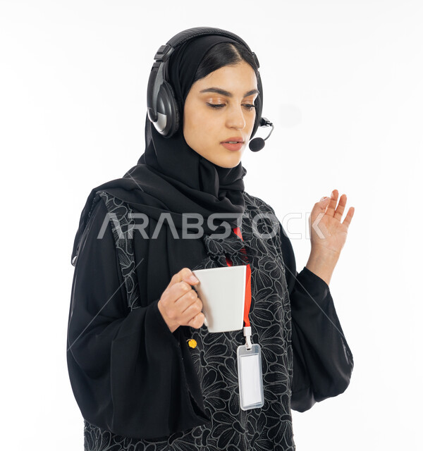 التعبير عن الذات، الهوية الشخصية والبطاقة التعريفية للموظفين, بورتريه مقرب لإمرأة عربية خليجية اماراتية ترتدي العباءة السوداء وسماعة التواصل تعمل في خدمة العملاء, الرد على الأسئلة والاستفسارات, سيدة سعودية تشرب كوب من القهوة الساخنة, خلفية بيضاء