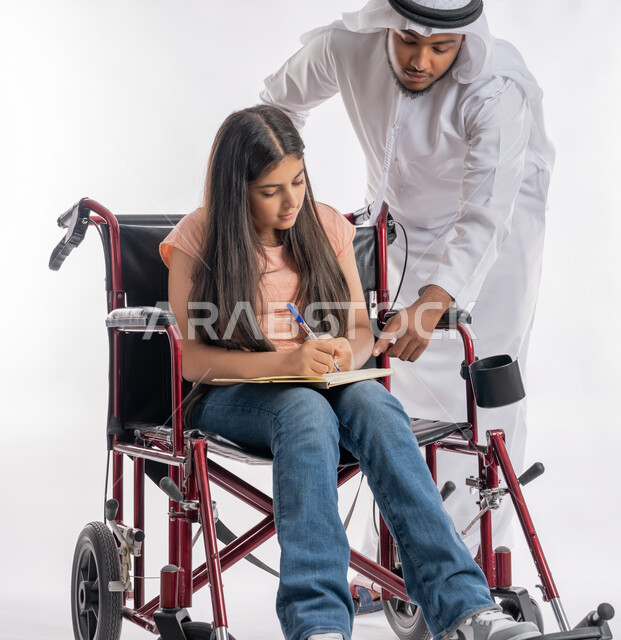 دعم المجتمع الاماراتي للمعاقين وتعليمهم, تنمية مهاراة الكتابة لذوي الاحتياجات الخاصة, تقديم الدعم والمساعدة لأصحاب الهمم, بورتريه لرجل عربي خليجي اماراتي يرتدي الغترة والكندورة يقوم بمساعدة ابنته المقعدة لأداء الواجبات المدرسية, خلفية بيضاء