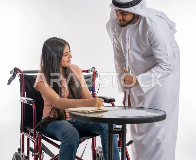 مساعدة أصحاب الهمم على أداء الواجبات المدرسية, مفهوم التعليم المنزلي لذوي الاحتياجات الخاصة, بورتريه لرجل عربي خليجي إماراتي يرتدي الكندورة يقوم بتشجيع ابنته المقعدة على الدراسة, فتاة إماراتية تجلس على كرسي متحرك, خلفية بيضاء