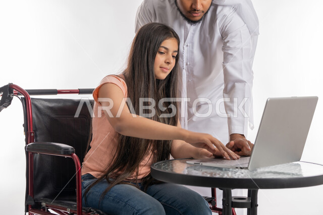 تنمية مهارات ذوي الهمم, التعليم عبر الأونلاين, قضاء وقت ممتع مع ذوي الاحتياجات الخاصة, بورتريه لفتاة عربية خليجية اماراتية مقعدة ترتدي الزي الكاجوال تجلس على كرسي متحرك تقوم باستخدام الحاسب المحمول برفقة والدها, دمج التقنية والتكنولوجيا مع التعلم, خلفية بيضاء