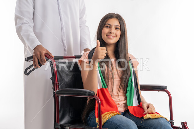 يوم العلم الاماراتي 3 نوفمير, يوم الاستقلال 2 ديسمبر, التباهي بالانتماء للوطن العربي, بورتريه لفتاة عربية خليجية إماراتية ترتدي الزي الكاجوال تجلس على كرسي متحرك وتضع على كتفها علم دولة الامارات بفخر واعتزاز, مساعدة ذوي الهمم على الحركة والتنقل, خلفية بيضاء