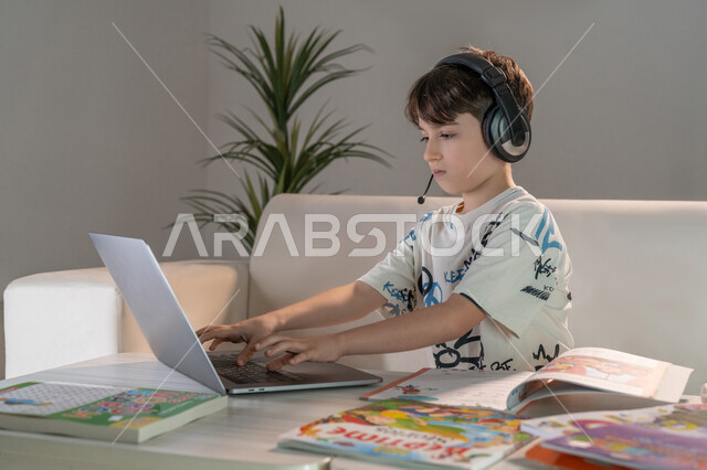 مشاهدة دورات تعليمية لتنمية المهارات الفنية والفكرية، متابعة الحصص الدراسية عبر الاونلاين، ولد عربي خليجي إماراتي يستخدم الحاسب المحمول لحل الواجبات المنزلية، دور التكنولوجيا في تطوير أساليب التعليم، السعي للتفوق والنجاح، دمج العلم مع التقنية