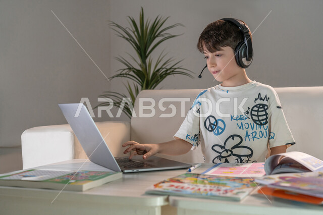 The role of technology in developing teaching methods, striving for excellence and success, integrating science with technology, watching educational courses to develop technical and intellectual skills, following up on online classes, an Emirati Gulf Arab boy using a laptop to solve homework