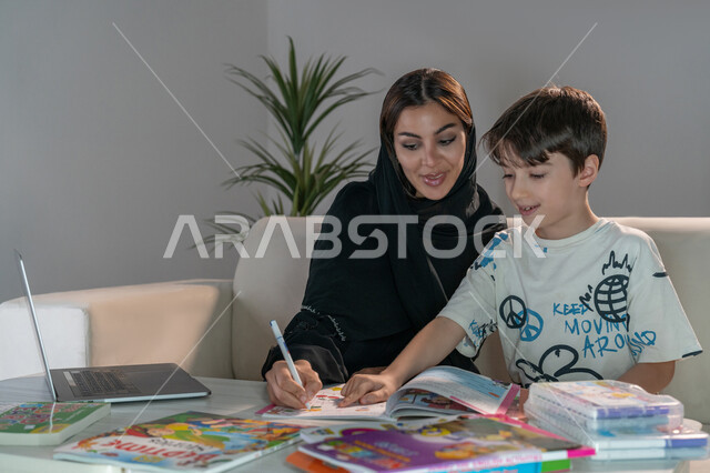 تنمية المهارات الثقافية والقدرات الفكرية للابناء، معلمة خصوصي لمتابعة الدروس في المنزل، دمج التعليم مع التقنية والتكنولوجيا، حل الواجبات المنزليه باستخدام الحاسب المحمول، أم عربية خليجة اماراتية محجبة تقوم بتعليم وتدريس ابنها