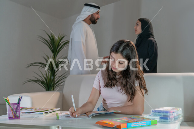 فتاة تقوم بالتلوين والانشطة الابداعية، استخدام ادوات ومعدات التلوين، رعاية وتشجيع وتطوير مهارات الابناء، قضاء اوقات عائلية ممتعة في المنزل، زوجان عربيان خليجيان إماراتيان يقومان بتبادل الآراء حول تنمية المهارات الفنية لإبنتهم