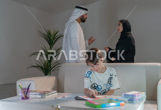 Boy coloring and creative activities, using coloring tools and equipment, caring for, encouraging and developing children's skills, spending enjoyable family time at home, an Arab Gulf Emirati couple exchanging views on developing their son's artistic skills