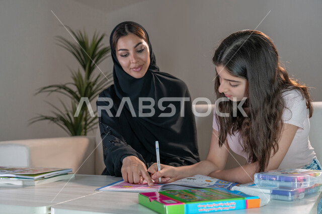 Private teacher to follow up on lessons at home, integrate education with technology, solve homework, a veiled Emirati Gulf Arab mother who teaches and teaches her daughter, develops the cultural skills and intellectual abilities of children