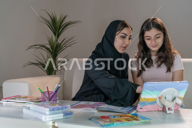 معلمة خصوصي لمتابعة الدروس في المنزل، دمج التعليم مع التقنية والتكنولوجيا، حل الواجبات المنزليه باستخدام جهاز التابلت، أم عربية خليجة اماراتية محجبة تقوم بتعليم وتدريس ابنتها، تنمية المهارات الثقافية والقدرات الفكرية للابناء
