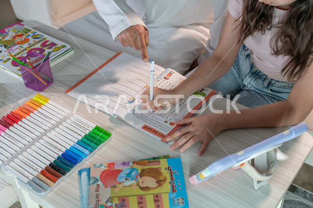 تنمية المهارات الثقافية والقدرات الفكرية للابناء، معلم خصوصي لمتابعة الدروس في المنزل، حل الواجبات المنزليه، أب عربي خليجي اماراتي يرتدي الكندورة والغترة يقوم بتعليم وتدريس ابنته