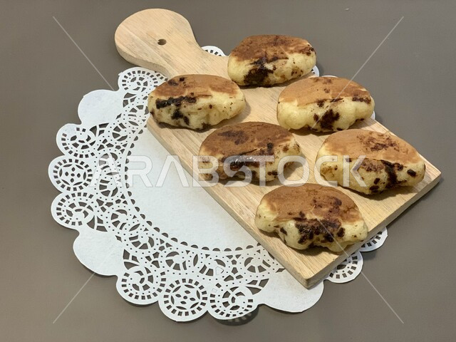 A plate filled with pieces of delicious cookies, oriental Arabic sweets, light snacks served with coffee, the art of serving dessert in Saudi Arabia, a fragile pie filled with delicious chocolate.
