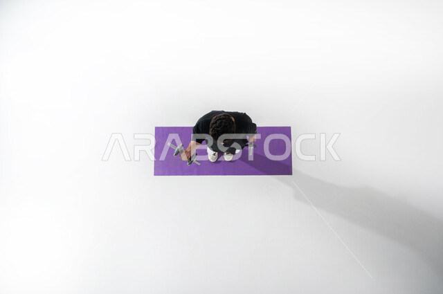 بناء العضلات بالتمارين الرياضية ، رفع الأثقال الحديدية، بورتريه لرجل عرب خليجي سعودي يرتدي ملابس رياضية يقوم برفع(الدمبلز)، المحافظة على اللياقة البدنية