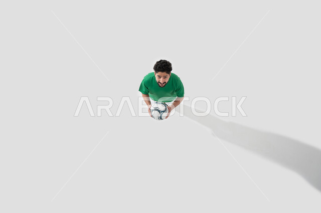 قضاء أوقات ممتعة ومسلية، ايماءات وجه تدل على السعاده والاستمتاع, بورتريه عامودي لشاب عربي سعودي خليجي, لعب رياضة كرة القدم, نشاط بدني للمحافظة على صحة الاجسام و اللياقة، خلفية بيضاء