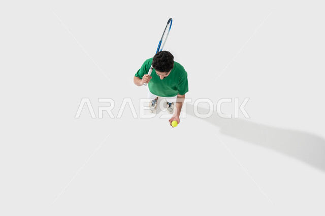 اللعب بسرعة وتركيز، بورتريه لشاب عربي خليجي سعودي يرتدي ملابس رياضية يحمل بيده مضرب تنس، ممارسة رياضات وانشطة بدنية ممتعة، تعابير وإيماءات تدل على الحماس والاندماج بالتمرين، المحافظة على الصحة والرشاقة الجسدية، خلفية بيضاء