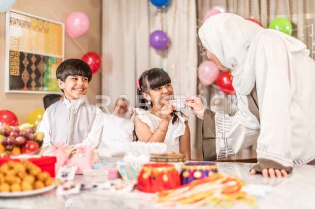 Sharing a wonderful atmosphere for a Saudi family inside the house celebrating Eid Al Fitr, Eid Al Fitr Mubarak, family visits and family gatherings, providing Eids and sweets, Gergean