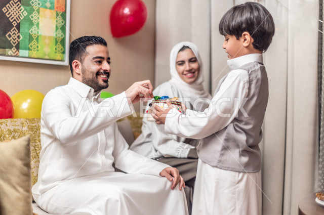 طفل سعودي خليجي سعيد ، يرتدي لباس العيد الانيق ، يأخذ العيدية  ، الاحتفال بعيد الفطر السعيد ، عيد الفطر المبارك  ،  تقديم العيديات و الحلوى ، القرقيعان