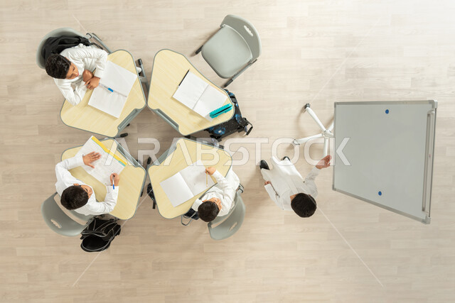 التعليم الدراسي في السعودية، بورتريه علوي عامودي لتلاميذ عرب خليجيون سعوديون يرتدون الثوب السعودي التقليدي، الانتباه الى صديقهم وهو يشرح فكرة ما، تأدية الواجبات المدرسية، الاهتمام بالعلم والتعلم، مفهوم الاجتهاد و طلب التفوق، خلفية بيج