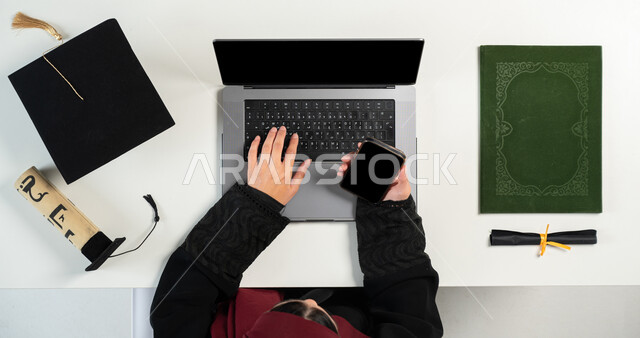 Ordering and selling products and shopping online, vertical portrait of a lady, a Saudi Arabian Gulf woman using a computer and phone, displaying a blank black screen, taking advantage of technology to obtain graduation supplies via the Internet, using telemarketing applications, white background