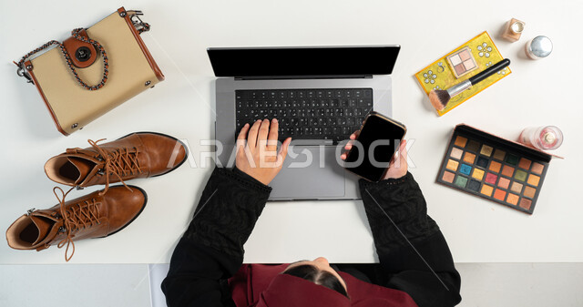 Obtaining personal items and cosmetics via the Internet, the concept of electronic shopping, a vertical overhead portrait of a Saudi Gulf Arab woman paying bills via mobile phone, integrating modern technologies into daily life, white background