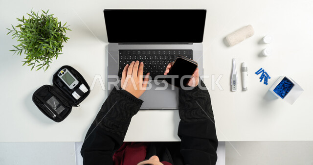 عرض جوال بشاشة سوداء فارغة، مفهوم العيادة الالكترونية، الاستشارات الطبية عبر المواقع الإلكترونية، بورتريه علوي عامودي لإمرأة عربية خليجية سعودية تقوم باستخدام الحاسب المحمول، الحصول على الأجهزة والمستلزمات الطبية أونلاين، خلفية بيضاء