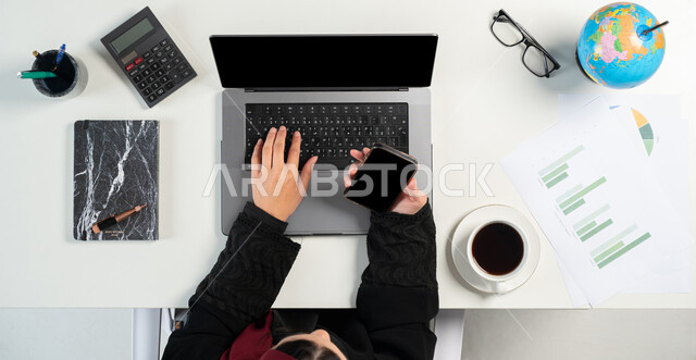 متابعة مخطط الرسم البياني للنمو الاقتصادي عبر الاجهزة التقنية، مراقبة الاقتصاد والمعلومات المالية، مفهوم الاستثمار المالي الالكتروني، بورتريه علوي عامودي لامرأة عربية خليجية سعودية تقوم بدراسة وتحليل الاحصائيات والرسوم البيانية عبر الحاسب المحمول والجوال، خلفية بيضاء