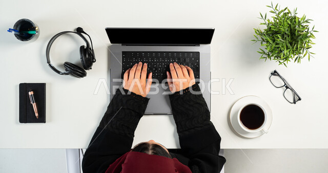 استعمال التقنيات الحديثة المتطورة, الحصول على سماعات الأذن والمشروبات الساخنة اونلاين، مفهوم الشراء عبر الانترنت، بورتريه علوي عامودي ليدي إمرأة عربية خليجية سعودية تقوم باستخدام الحاسوب المحمول للتسوق عبر المواقع الإلكترونية، عرض شاشة سوداء فارغة، خلفية بيضاء