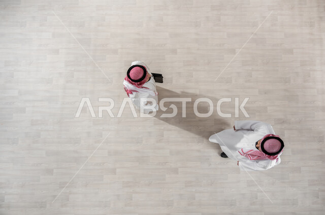 المتعة مع الأصدقاء, الانجاز والانتهاء من الدوام, بورتريه علوي عامودي لزملاء عمل عرب خليجيين سعوديين يرتديان الثوب التقليدي والشماغ, خروج الموظفين عند انتهاء أوقات الدوام الرسمية, التجول في ممرات الشركة, قضاء أوقات ممتعة في العمل, خلفية بيج