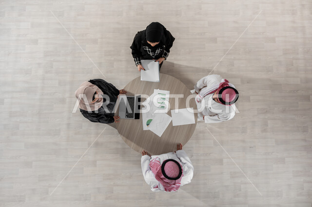 تبادل الخبرات والاتفاقيات الناجحة, التعاون والتفاهم بين الفريق, شرح المهام المطلوبة, بيئة العمل المريحة في الشركة, تنظيم وادارة جدول مفهوم العمل, بورتريه علوي عامودي لزملاء عمل عرب خليجيين سعوديين في اجتماع, ارتداء اللباس السعودي التقليدي, خلفية بيج