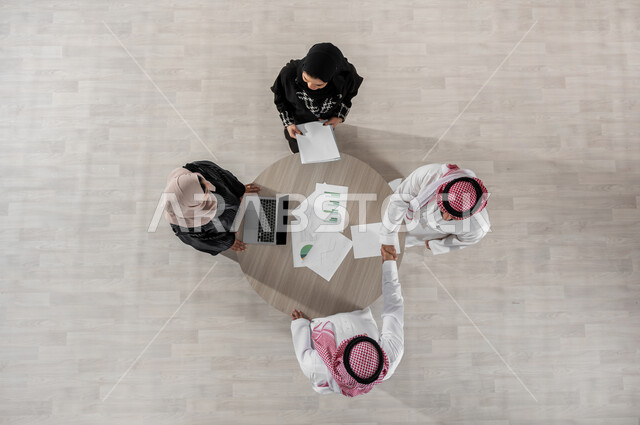 التعاون والتفاهم بين الفريق, شرح المهام المطلوبة, بيئة العمل المريحة في الشركة, تنظيم وادارة جدول مفهوم العمل, تبادل الخبرات والاتفاقيات الناجحة, بورتريه علوي عامودي لزملاء عمل عرب خليجيين سعوديين في اجتماع, ارتداء اللباس السعودي التقليدي, خلفية بيج