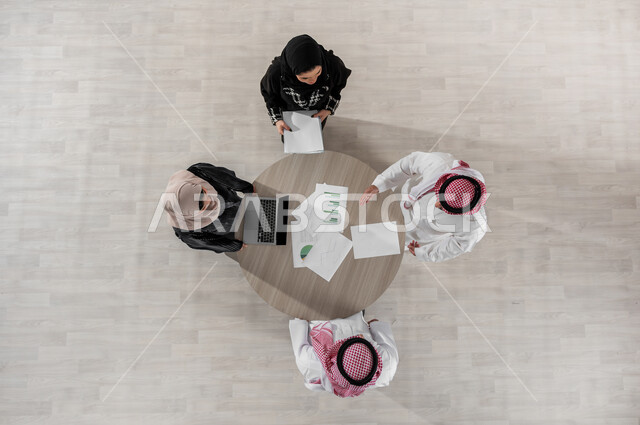 بيئة العمل المريحة في الشركة, تنظيم وادارة جدول مفهوم العمل, شرح المهام المطلوبة, التعاون والتفاهم بين الفريق, تبادل الخبرات والاتفاقيات الناجحة, بورتريه علوي عامودي لزملاء عمل عرب خليجيين سعوديين في اجتماع, ارتداء اللباس السعودي التقليدي, خلفية بيج
