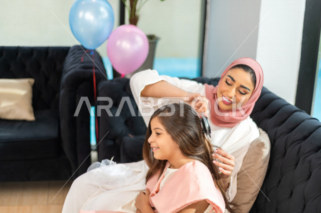 A wonderful sharing of a mother with her daughter on the morning of Eid, wearing the traditional Saudi dress, Eidiya, and Gergean