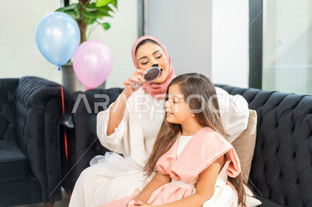A wonderful sharing of a mother with her daughter on the morning of Eid, wearing the traditional Saudi dress, Eidiya, and Gergean