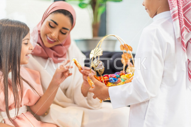 Sharing a wonderful atmosphere for a Saudi family inside the house celebrating Eid Al Fitr, Eid Al Fitr Mubarak, family visits and family gatherings, offering Eids and sweets, Gergean