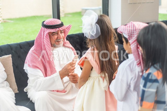 طفلة سعودية خليجية سعيدة ترتدي لباس العيد الانيق ، تشارك الاجواء الاحتفالية الخاصة بعيد الفطر المبارك ، الاحتفال بعيد الفطر السعيد ، عيد الفطر المبارك  ،  تقديم العيديات و الحلوى ، القرقيعان