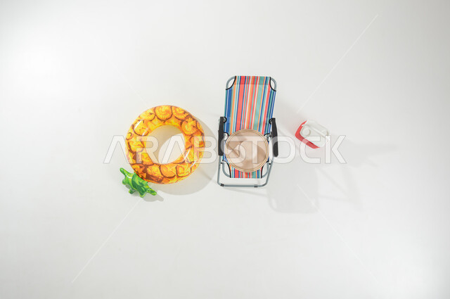 عطلة صيفية ممتعة , إجازة على الشاطئ , بورتريه علوي عامودي لكرسي و عوامة سباحة , أجواء الصيف السعيدة , خلفية بيضاء