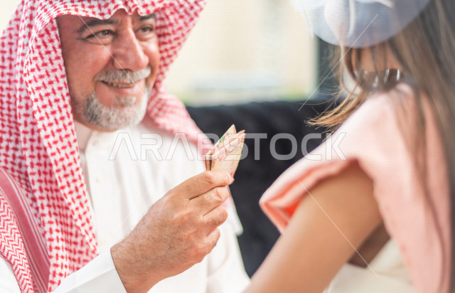 تقديم العيدية للأطفال في عيد الفطر المبارك ، أجواء رائعة لعائلة سعودية داخل المنزل تحتفل بعيد الفطر السعيد ، عيد فطر مبارك ،  الزيارات العائلية وتجمعات الأسر ،  تقديم العيديات و الحلوى ، القرقيعان