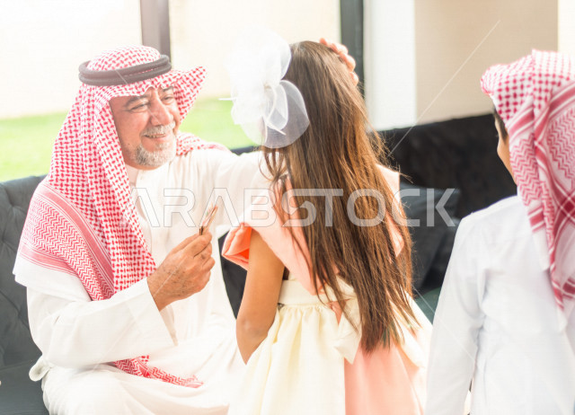 طفلة سعودية خليجية سعيدة ترتدي لباس العيد الانيق ، تشارك الاجواء الاحتفالية الخاصة بعيد الفطر المبارك ، الاحتفال بعيد الفطر السعيد ، عيد الفطر المبارك  ،  تقديم العيديات و الحلوى ، القرقيعان