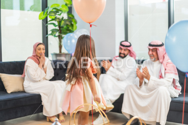 طفلة سعودية خليجية سعيدة ترتدي لباس العيد الانيق ، تشارك الاجواء الاحتفالية الخاصة بعيد الفطر المبارك ، الاحتفال بعيد الفطر السعيد ، عيد الفطر المبارك  ،  تقديم العيديات و الحلوى ، القرقيعان