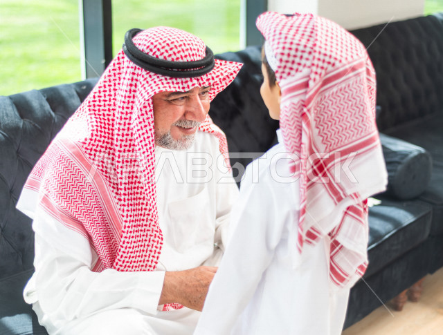 طفل سعودي خليجي سعيد ، يرتدي لباس العيد الانيق ، يقبل جده و يهنئه بقدوم العيد  ، الاحتفال بعيد الفطر السعيد ، عيد الفطر المبارك 