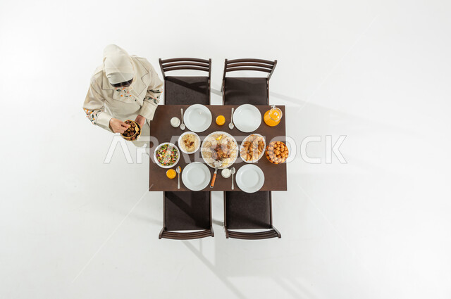 Iftar in the holy month of Ramadan, vertical portrait of a Saudi Gulf Arab woman wearing traditional dress and hijab, holding a lantern in her hands, preparing the dining table, Ramadan atmosphere in Saudi Arabia, white background