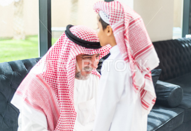 طفل سعودي خليجي سعيد ، يرتدي لباس العيد الانيق ، يقبل جده و يهنئه بقدوم العيد  ، الاحتفال بعيد الفطر السعيد ، عيد الفطر المبارك 
